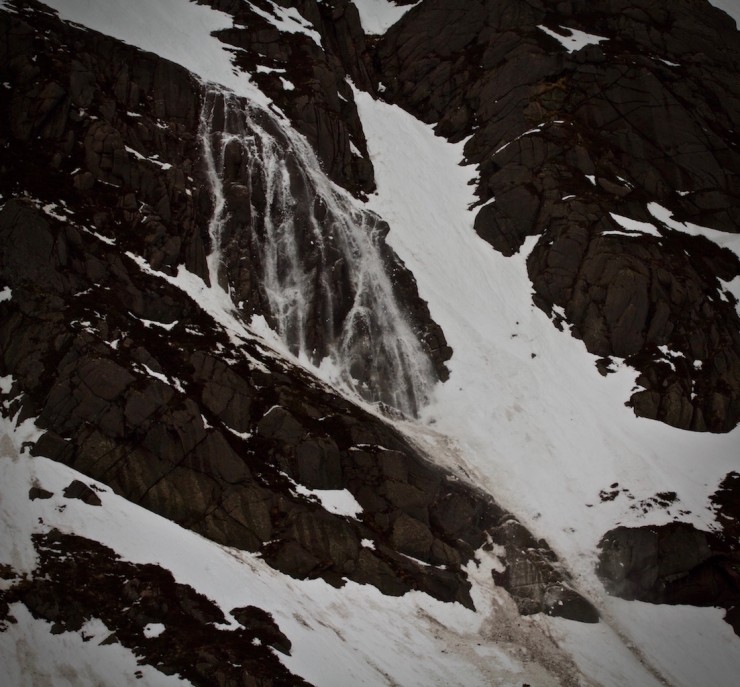 Snow pours through a crag.